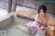 A woman in a pink dress sitting in a hot tub.