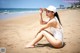 A woman in a white bathing suit sitting on a beach.