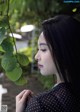 A woman holding a plant in front of her face.