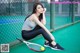 A woman sitting on a tennis court holding a tennis racket.