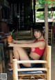 A woman in a red bikini sitting on a wooden chair.