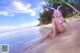 A woman in a bikini sitting on the beach.