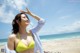 A woman in a yellow bikini standing on a beach.